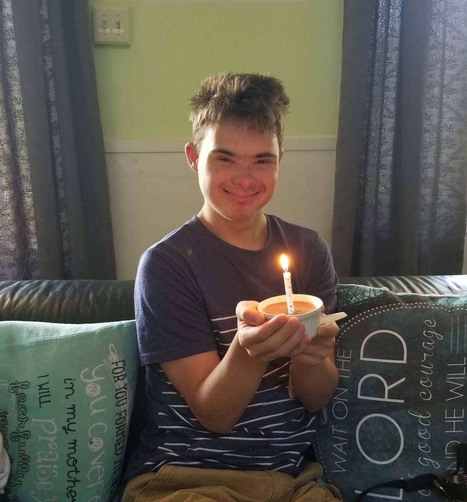 a boy holding a lit candle and smiling